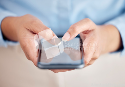 Image of Unrecognizable business woman holding and working on a phone in their hand while standing inside a office at work. Unrecognizable female typing a message and using social media showing their screen