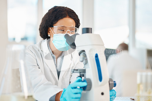 Image of I hope my theory is right. a young scientist using a microscope in a lab.