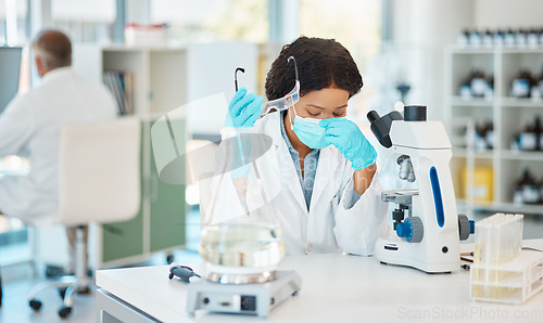 Image of This is harder than I expected. a young scientist looking stressed out while working in a lab.