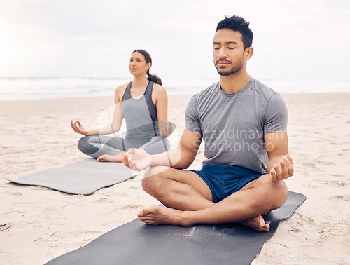 Image of Challenging mind and body in equal measure. a young couple meditating while practising yoga together on the beach.