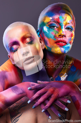 Image of You are the canvas. Studio shot of two young women posing with multi-coloured paint on her face.