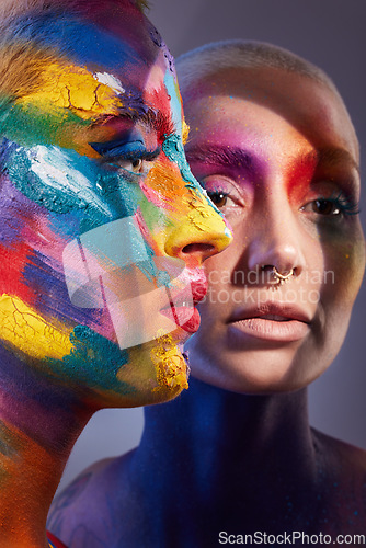 Image of Feeling bright. Studio shot of two young women posing with multi-coloured paint on her face.