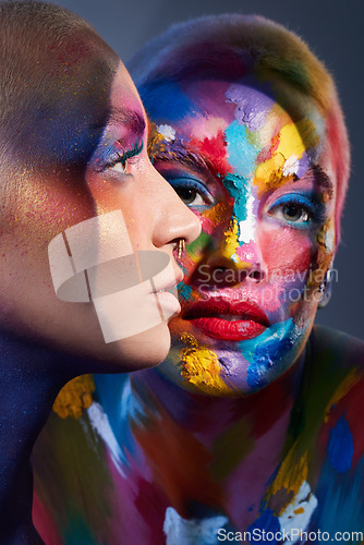 Image of Everyone needs a little colour in their life. Studio shot of two young women posing with multi-coloured paint on her face.