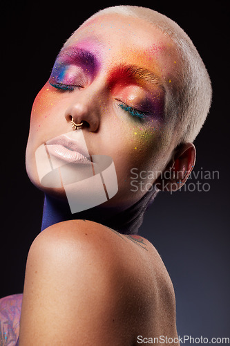 Image of Live life colourfully. Studio shot of a young woman posing with multi-coloured paint on her face.