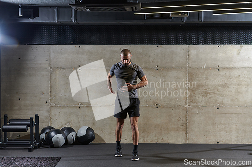 Image of A muscular man working stretching exercises for his arms and body muscles in modern gym