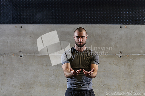 Image of A muscular man working stretching exercises for his arms and body muscles in modern gym