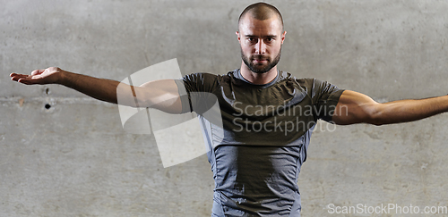 Image of A muscular man working stretching exercises for his arms and body muscles in modern gym