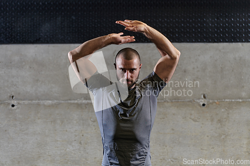 Image of A muscular man working stretching exercises for his arms and body muscles in modern gym