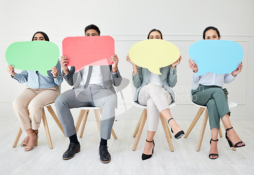 Image of Let your voice be heard. Portrait of a group of businesspeople holding speech bubbles while sitting in line against a grey background.