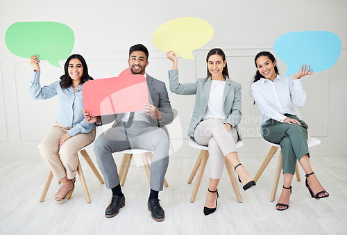 Image of Say it again for the people in the back. Portrait of a group of businesspeople holding speech bubbles while sitting in line against a grey background.