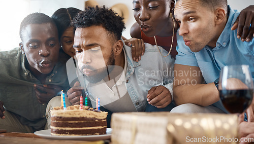 Image of He needs a little help. a young man blowing out his birthday candles at his party at home.