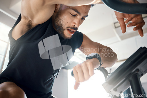 Image of Times up for today. Low angle shot of a sporty young man checking his watch while exercising in a gym.