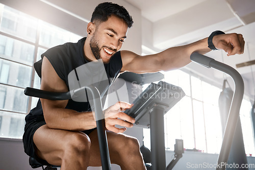 Image of Im ready to up the intensity now. Low angle shot of a sporty young man working out on an exercise bike in a gym.