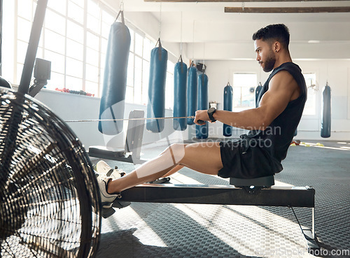 Image of Commit to be fit. a sporty young man exercising on a rowing machine in a gym.
