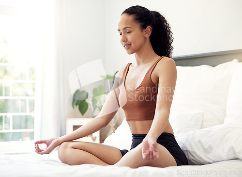 Image of All you need to do is breathe. a young woman meditating while sitting on her bed at home.