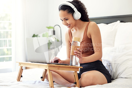 Image of Ive found a new show to watch. a young woman using a laptop while sitting on her bed at home.