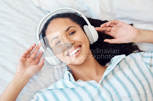 Image of Allowing the music to take me away. a young woman listening to music while sitting on her bed at home.