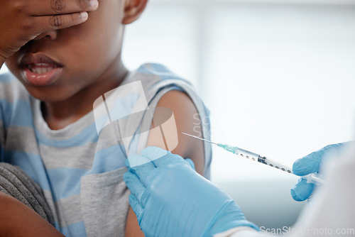 Image of Trying to put on a brave face. a little boy looking scared while getting an injection on his arm from a doctor.