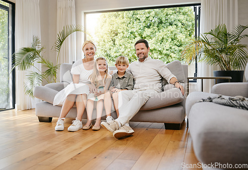 Image of Fullbody young smiling caucasian family sitting on the couch together and bonding in a home lounge on a weekend. Mother and father sitting with children on a sofa