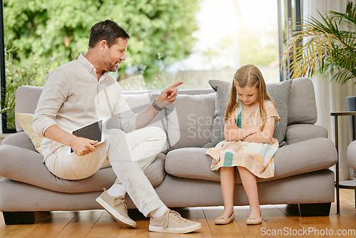 Image of Father scolding daughter over screen time on digital tablet. Little girl looking sad while dad takes away tablet. Child struggling with internet or mobile games addiction
