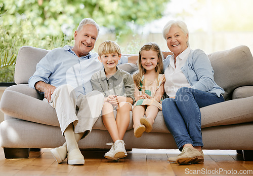 Image of Portrait of an affectionate family of four sitting comfortable on their sofa in the living room at home. A grandmother, grandfather, grandson and granddaughter enjoying quality time together and bond