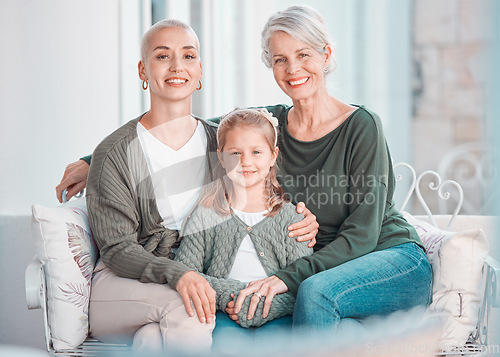 Image of Three generations of females sitting together and looking at the camera. Portrait of an adorable little girl bonding with her mother and grandmother at home. Enjoying a visit with her granddaughter