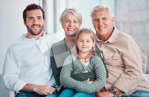 Image of Cute little girl sitting on the couch together with family. Happy child sitting with her father and grandparents at home. Caucasian family smiling while relaxing together during a visit