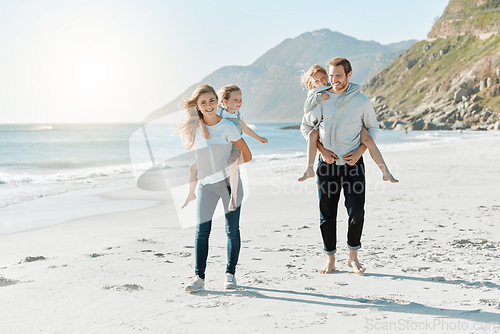 Image of Today is all about the things we love doing as a family. a couple carrying their daughters on their backs while at the beach.