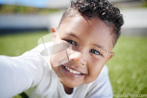 Image of Look whos taking selfies now. a little boy taking a selfie while lying on the grass outside.