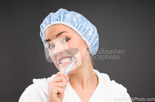 Image of The morning routine takes forever. a young woman brushing her teeth against a studio background.