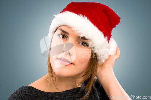 Image of Christmas has come early. a young woman wearing a christmas hat against a studio background.