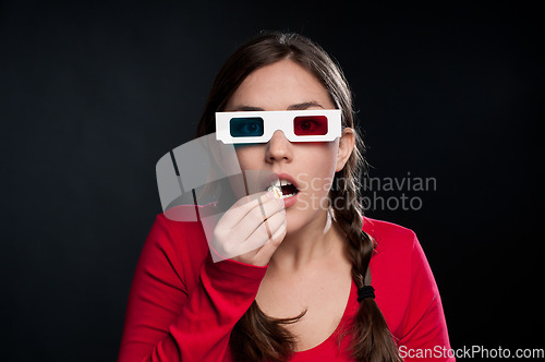 Image of A gripping thriller. a young woman eating popcorn against a studio background.