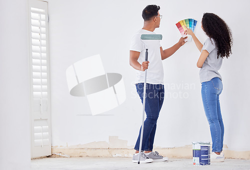 Image of We need a little color in here. a young couple looking at color swatches while painting a room.