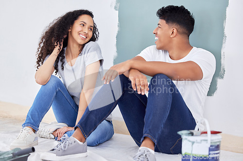 Image of I cant believe how good we are at this. a young couple painting a wall in a room together.