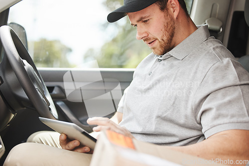 Image of Whats the address again. a handsome young delivery man using a tablet while sitting in his van.