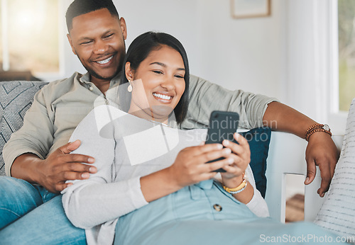 Image of They even have joint social media accounts. a young couple using a cellphone while relaxing together at home.