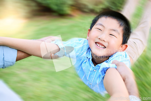 Image of Hes as happy as ever. a little boy being swung by his parent in their garden at home.