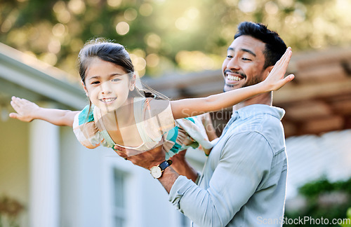 Image of I can fly if I want. a young father holding up his daughter in the garden outside.