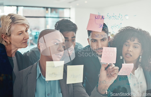 Image of Lets work on this one right here. a diverse group of businesspeople standing together in the office and using a visual aid to brainstorm.