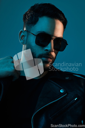 Image of Cool is always in fashion. Conceptual shot of a stylish young man posing in studio against a blue background.