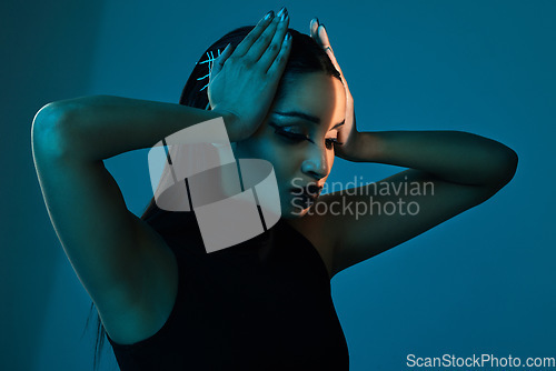 Image of Style dilemma. Conceptual shot of a stylish young woman posing in studio against a blue background.