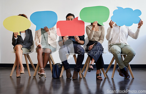 Image of Everyone has a right to their own opinion. a group of young businesspeople holding speech bubbles while waiting in line.