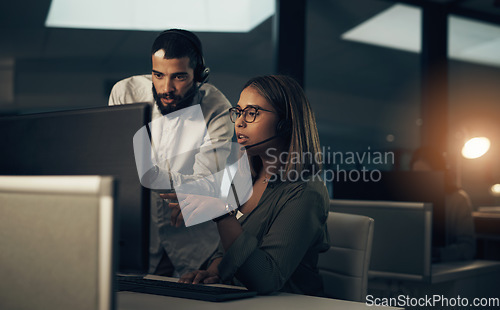 Image of Lets troubleshoot some more. two call centre agents working together in an office at night.