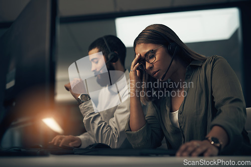 Image of Some customers are just a pain to deal with. a call centre agent looking stressed out while working in an office at night.