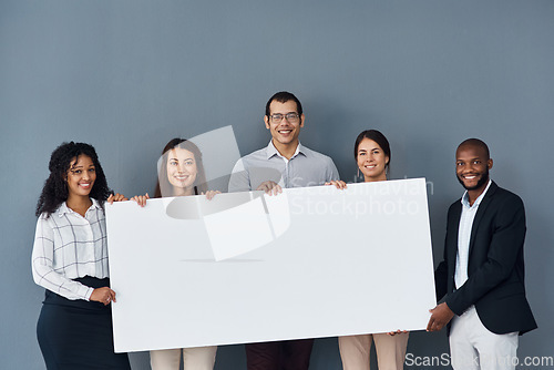 Image of Well show everyone your message. Portrait of a group of businesspeople holding a black poster while standing against a grey background.