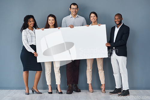 Image of Why not advertise your business on this platform. Portrait of a group of businesspeople holding a black poster while standing against a grey background.