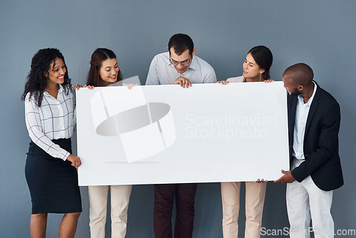 Image of How you brand your business definitely matters a lot. Portrait of a group of businesspeople holding a black poster while standing against a grey background.