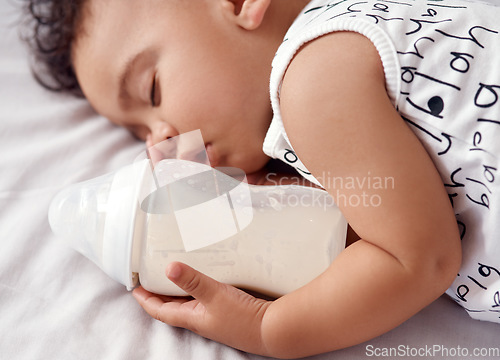 Image of Snack time turned into nap time. an adorable baby boy sleeping with his bottle of milk on the bed at home.