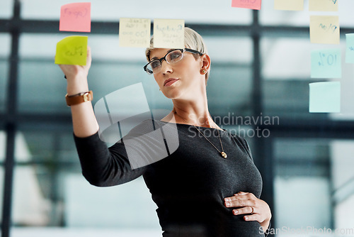 Image of Making plans for the future of her business. a pregnant businesswoman brainstorming with notes on a glass wall in an office.