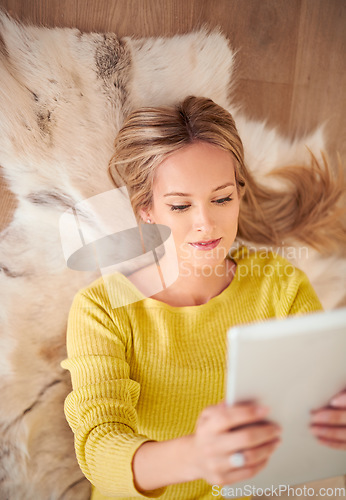 Image of She looks good fom every angle. A young woman lying on the ground holding a digtal tablet.